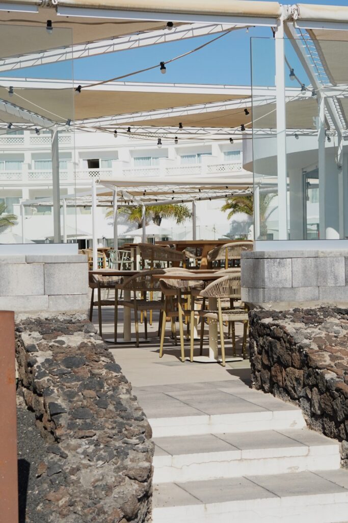 Relaxing open-air cafe seating with ocean view in Lanzarote, Spain.